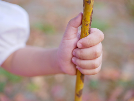 Little Asian baby girl hand holding tightly on a metalic chain while going on a swing at a playgroundの写真素材