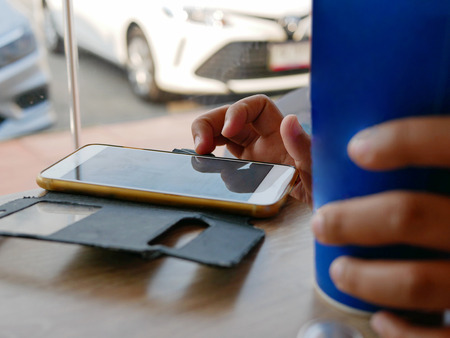 Lifestyle of sitting and using a smartphone in a fast food restaurant with a cup of carbonated soft...
