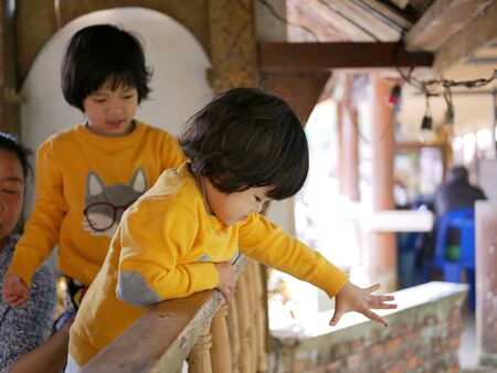 Little Asian baby girl enjoys feeding fishes in the river with fish foodの写真素材