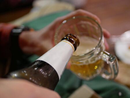 Selective focus of bottle of beer pouring that frosty cold beer into a glass at a restaurantの写真素材