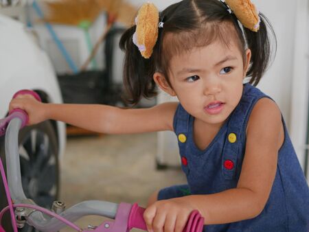Little baby girl enjoys riding the first bicycle, with training wheels, in her lifeの写真素材