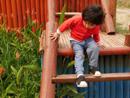 Little Asian baby girl going down stairs on her own while holding onto the railingの写真素材