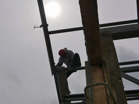 A structural steel worker working on a high rooftop for a house roof structure installation