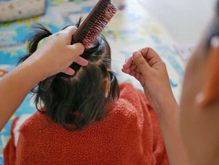 Mother's hands doing her little daughter's hairs using hair bands - love and care from mom