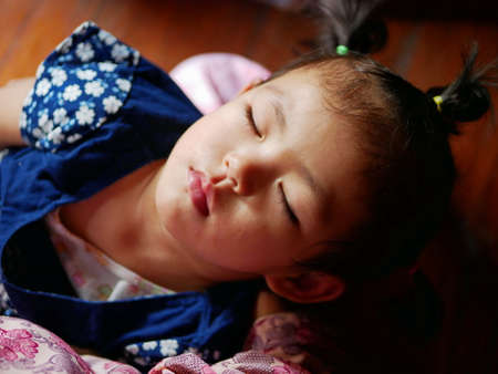 Little baby girl, 2 years old, sleeping in her mother's armの写真素材