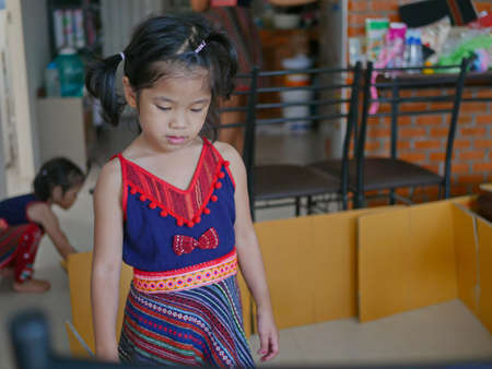 Little girl, 4 years old, is thinking about how she can build a house out of cardboard boxes by herself, at homeの写真素材