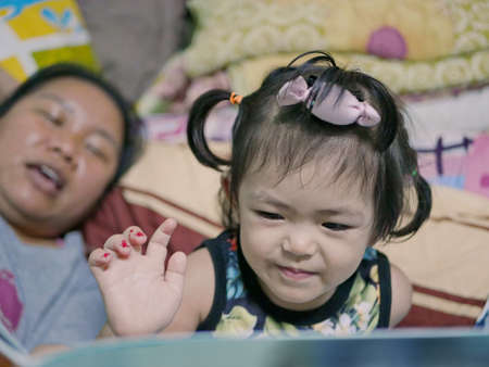 A baby girl, 2 years old, about to point at the illustration in a book, being interactiveの写真素材