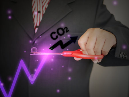 A businessman decides to use scissors to cut or eliminate the increase or rise of carbon dioxide in his business to maintain a level of the gas. Reduce CO2 emission concept.の写真素材
