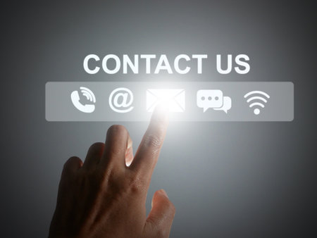 Contact us or Customer support concept. Finger tapping on a virtual screen of contact icons:  phone,...