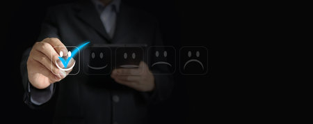 A Businessman's Hand Holds a Stylus, Marking the Perfect 'Tick' on One Happy Smiling Face. Capture Your Customers' Hearts with Unmatched Quality and Serviceの写真素材