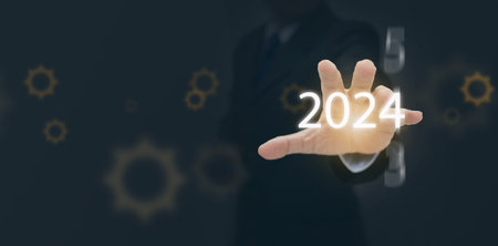 A businessman reaches his hand out to the starting new year 2024. Happy new year and welcome new business opportunities, goals,  and  visionsの写真素材