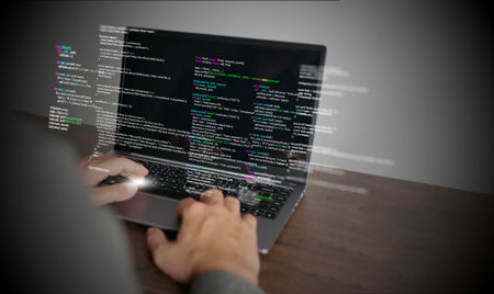 Hands of a programmer types on a laptop displaying programming code, symbolizing coding tech,...