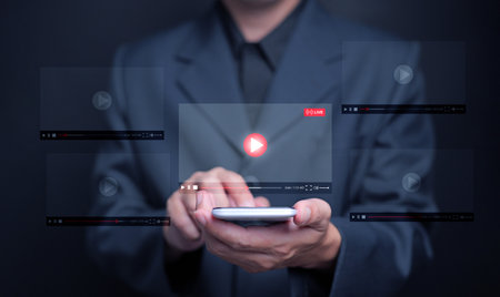 Watching online video is now embedded in everyday life. A man watches a video, live streaming, from his smartphone for entertainment, including streaming movies, live shows, online lessons, and musicの写真素材