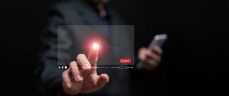 Watching online video is now embedded in everyday life. A man watches a video from his smartphone for entertainment, including streaming movies, live shows, online lessons, and musicの写真素材