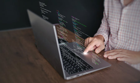Hands of a programmer types on a laptop displaying programming code, symbolizing coding tech, software development, web applications. IT solutions, and digital technologyの写真素材