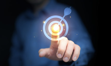 Glowing bullseye target with dart icon touched by business hand, representing focus, success, strategy, and determination. Ideal for leadership, achievement, and professional growth concepts.の写真素材