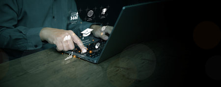 Hands using laptop with education graphic icons, representing e-learning, knowledge sharing, and innovation in digital business school and career development.の写真素材