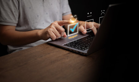 A person selecting five-star rating on a laptop, symbolizing customer satisfaction, online feedback,...
