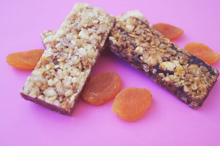 Food Dessert Bar with muesli cereals and chocolate with dried apricot on pink background paper isolate top viewの写真素材