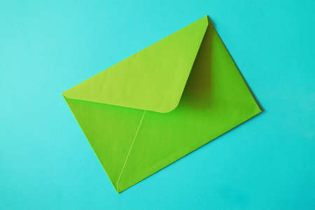 Green envelope on blue background, flat lay. Space for text.の写真素材
