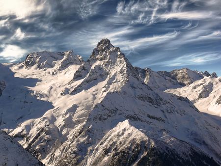 Top of the Caucasus mountain range. Against the background of the sky. On the rugged slopes -...
