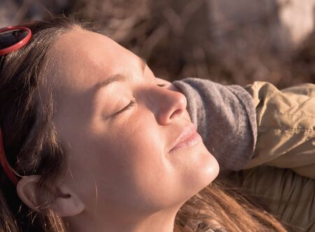 Young beautiful girl smiling. Squinting in the glow of the sunset. Portrait of a close-up.の写真素材
