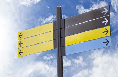 Colorful plastic informational signs with arrows. Show the direction. Against the blue sky with cloudsの写真素材