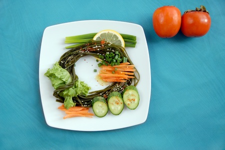 Seaweed with a cucumber, carrots, an onions, salad, a lemon and spices. Sideways two persimmonsの写真素材