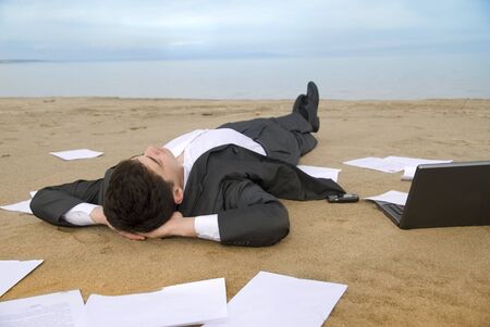 young guy in a business suit is on the beach among the scattered papersの写真素材