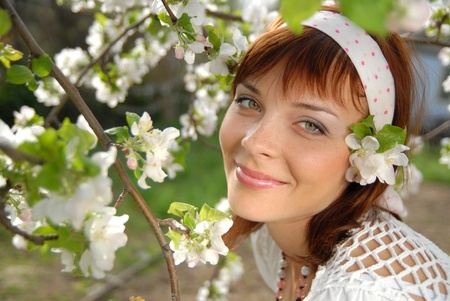 Beautiful, young woman smiles. Beside her, a branch of apple blossomsの写真素材