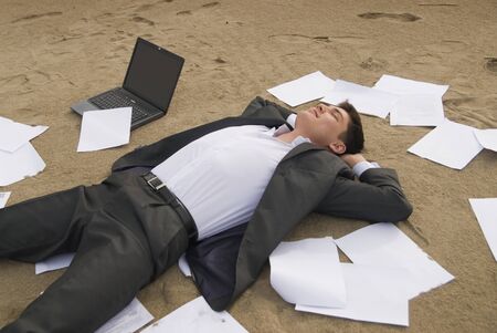 young guy in a business suit is on the beach among the scattered papersの写真素材