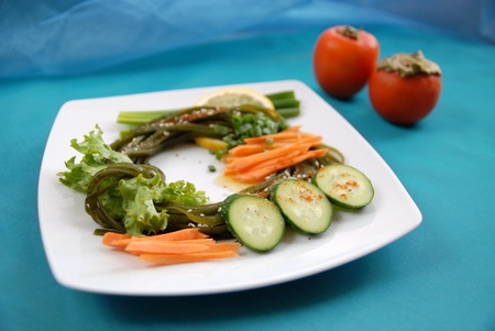 Seaweed with a cucumber, carrots, an onions, salad, a lemon and spices. Sideways two persimmons.の写真素材