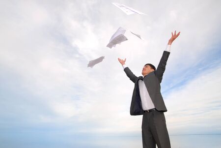 young guy in a business suit with joy throwing papers in the skyの写真素材