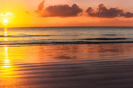 Sunset over the ocean. Quiet beautiful landscape with the golden sunset with reflection of the sun path on the water.の写真素材