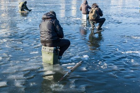 man on winter fishing, people on the ice of the frozen lake, fishermen, urban landscape,の写真素材