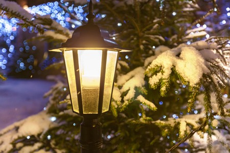 Street lamp.  Switched-on street lamp against decorated Christmas tree and garlands in the snow close up.の写真素材