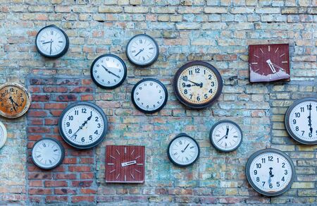 Multiple clock. Plurality of the different clocks on the old brick wall.