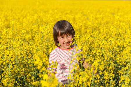 children in the field with the flowering yellow flowers of rapeの写真素材