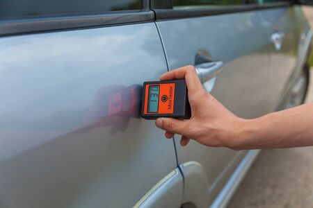 checking the body and doors of the car, the man measures the car's body with the appliance, car...