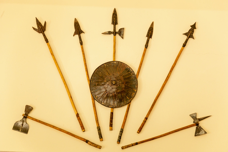 A set of medieval weaponry. Spears, axes, shield on beige background.