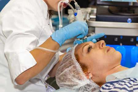 Ukraine Kiev 22 September 2017: Cosmetology doctor makes the procedure a woman face cleaningのeditorial素材