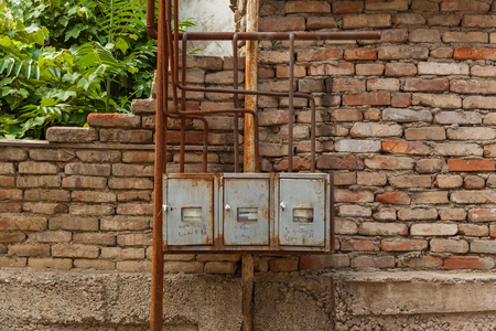 Electric meters in a metal case against a brick wall background. Electric meters.の写真素材