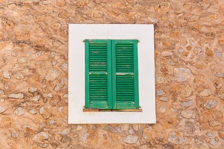 Closed green shutters against the backdrop of a stone wall. Green shutters.