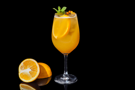 Alcoholic orange juice on a black background decorated with an orange slice and mint. Alcoholic orange juice on a black background.の写真素材