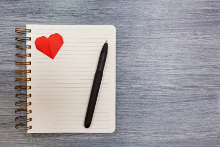 Notepad with red hearts and a pen lay on a table. Notepad with hearts.の写真素材