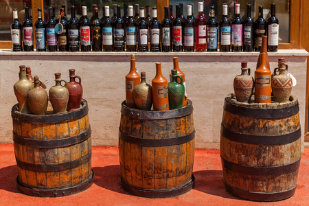 Batumi Georgia 11 July 2017: Bottles of Georgian wine standing on a wooden barrel on the background of shelves with bottlesのeditorial素材