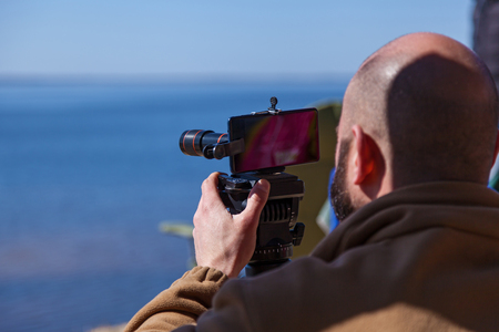 A man adjusts the smartphone on a tripod with lenses. The photographer travels taking pictures of the landscape using a mobile phoneの写真素材