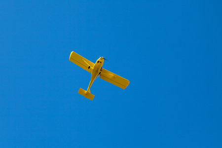 Light yellow aircraft flies in the blue sky