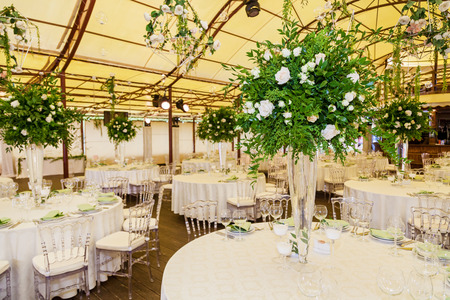 Design and decor decoration of the wedding celebration with white roses, green leaves, candles and bouquets of flowersの写真素材