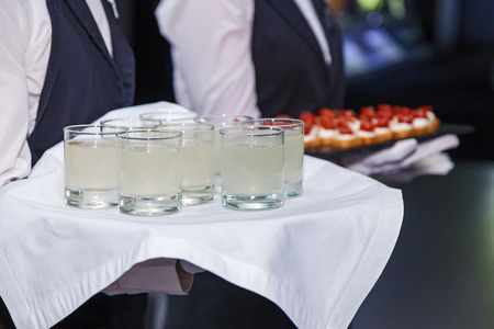 Waiter holding a tray offers guests at the event a glass of lemonadeの写真素材